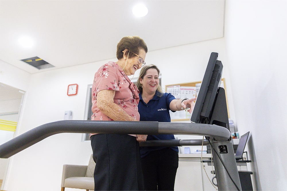 Funcionária ajudando senhora fazer caminhada na esteira